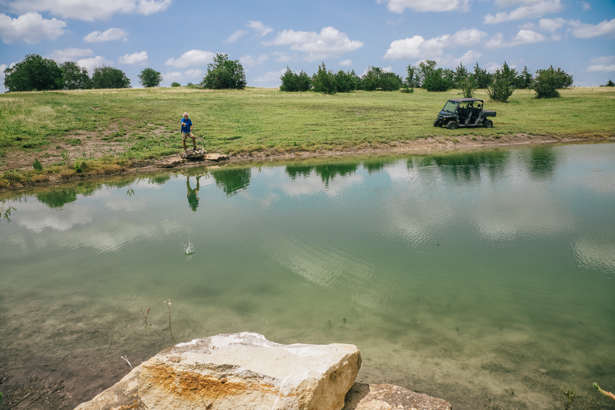 Man fishing from rock, wide pond view — Lot 4