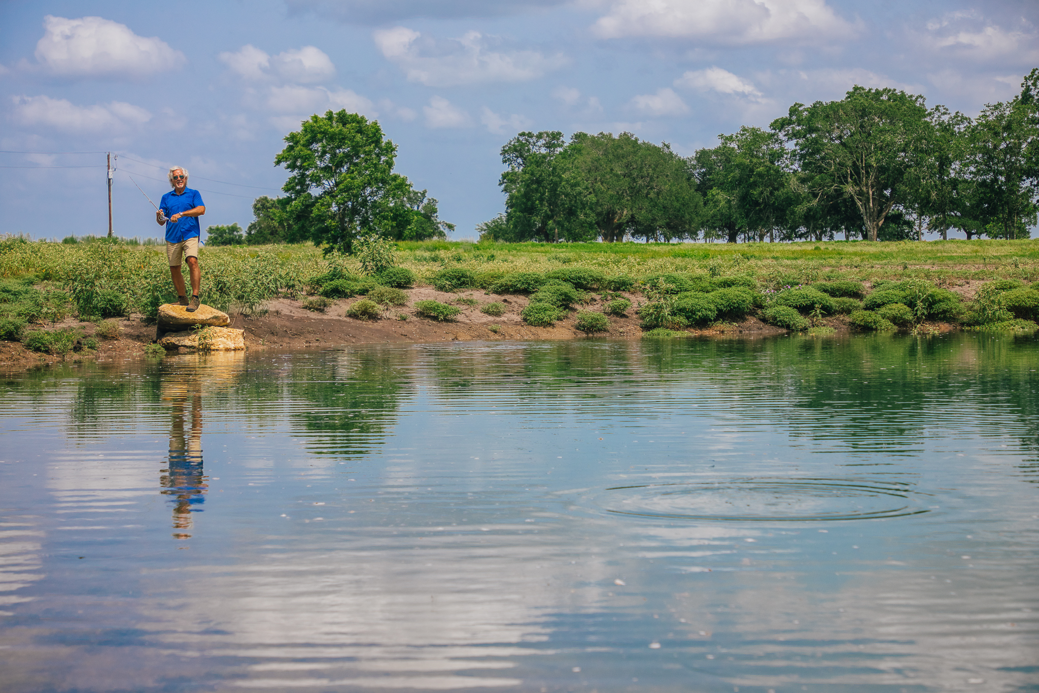 Man fishing from rock, strong reflection — Lot 1 pond
